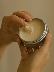 Hand holding a jar of cream with a beige background