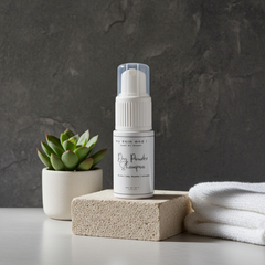 Skincare product bottle with a plant and towel on a dark background