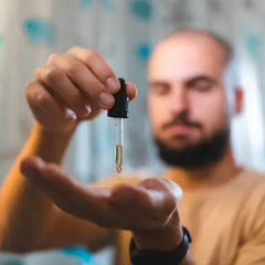 Man holding a dropper with a clear liquid, blurred background